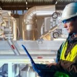 Worker in chemical plant reviews results on laptop