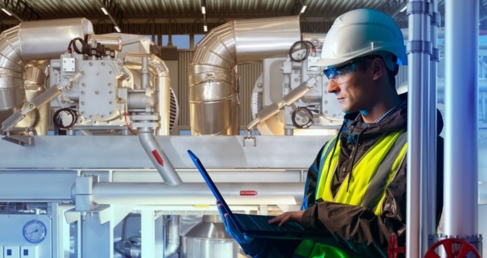 Worker in chemical plant reviews results on laptop