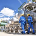 2 Workers in jumpsuits at an industrial plant