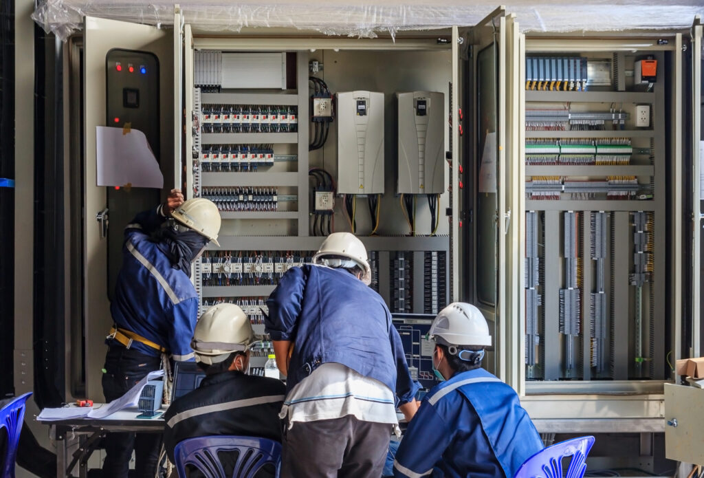 Men working in PLC Cabinet ICS Cyber